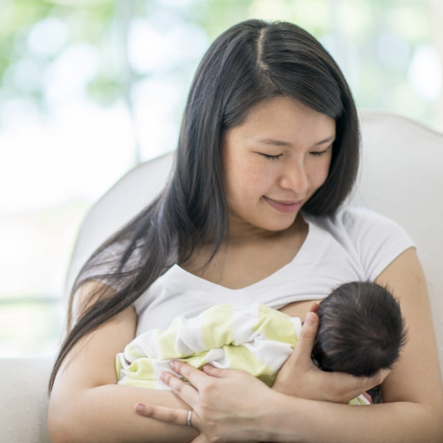 A woman breastfeeding her newborn baby. For breast milk supply support, try UpSpring supplements for lactation.