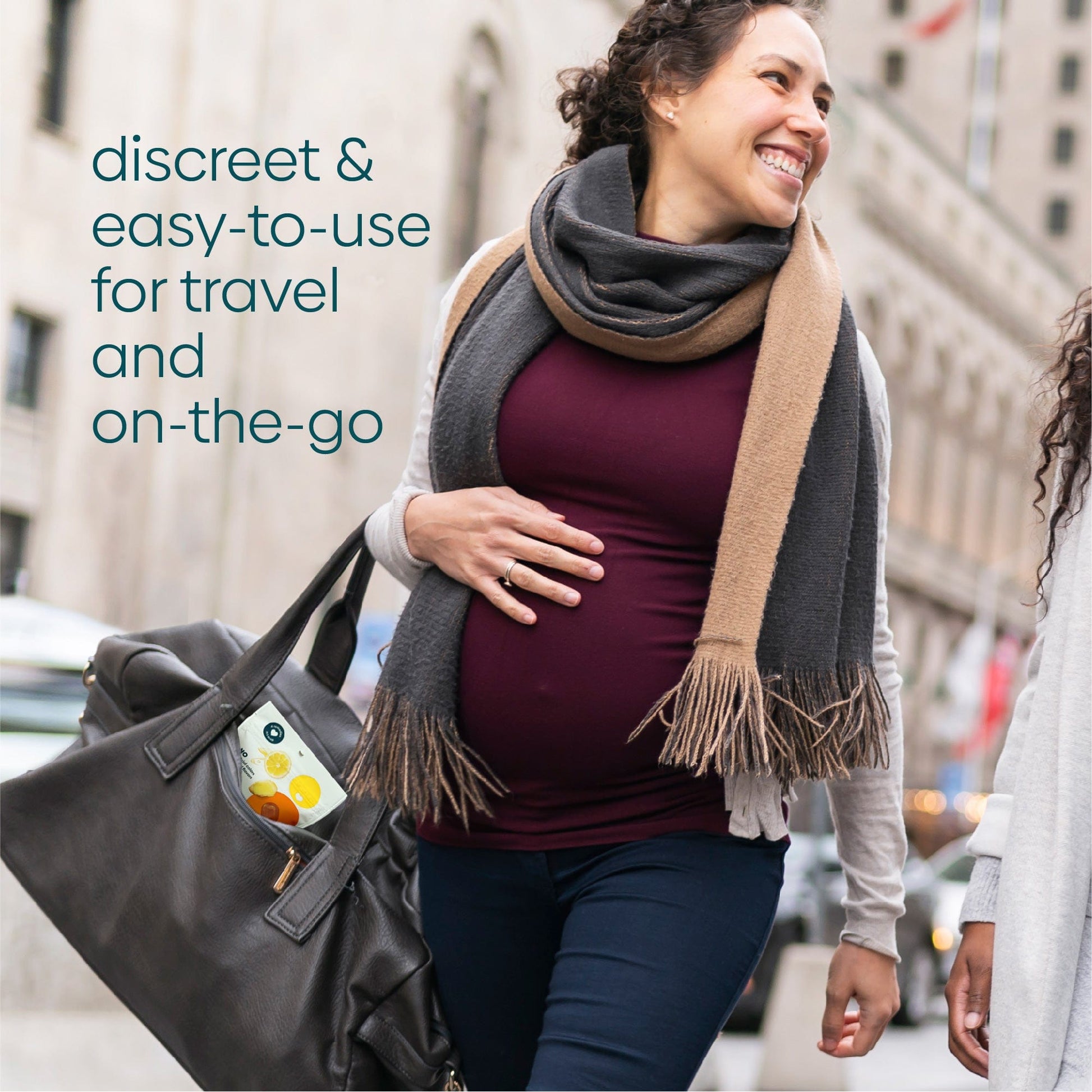 A pregnant woman holding a large bag with Stomach Settle drops inside walks happily with a friend 